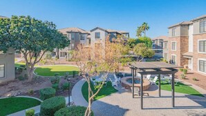 A residential complex with multiple two-story houses, a well-maintained lawn, and a gazebo with seating.