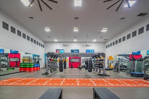Ett gym med olika typer av träningsutrustning, inklusive en stång för chins och boxningssäckar.