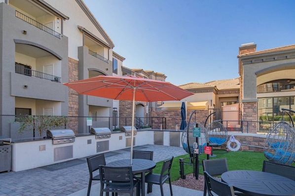 An outdoor patio with a grill, seating area, and a swing chair.