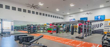 A gym with various exercise equipment, a mirrored wall, and motivational posters.