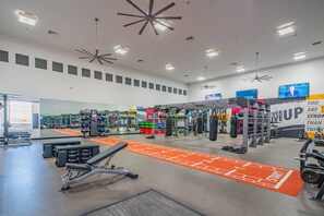 A gym with various exercise equipment, a mirrored wall, and motivational posters.
