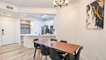 A modern kitchen with white cabinets, a stainless steel refrigerator, and a microwave.