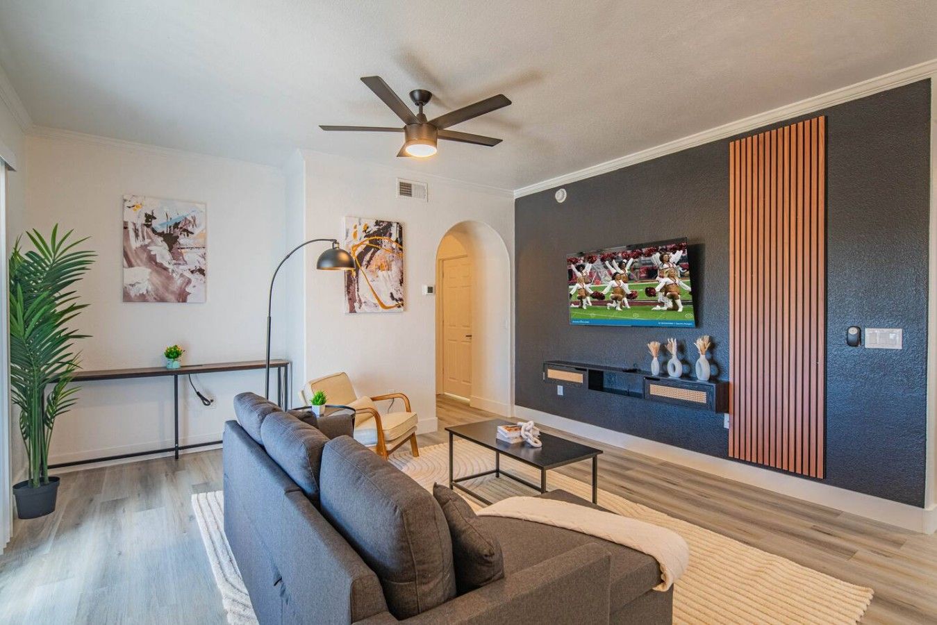A modern living room with a sofa, coffee table, and a flat-screen TV mounted on the wall.
