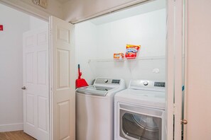 A laundry room with two front-loading washing machines and a red mop on a shelf. - Near Attractions |Balcony, Pool, Gym, Parking, W/D (Glendale)