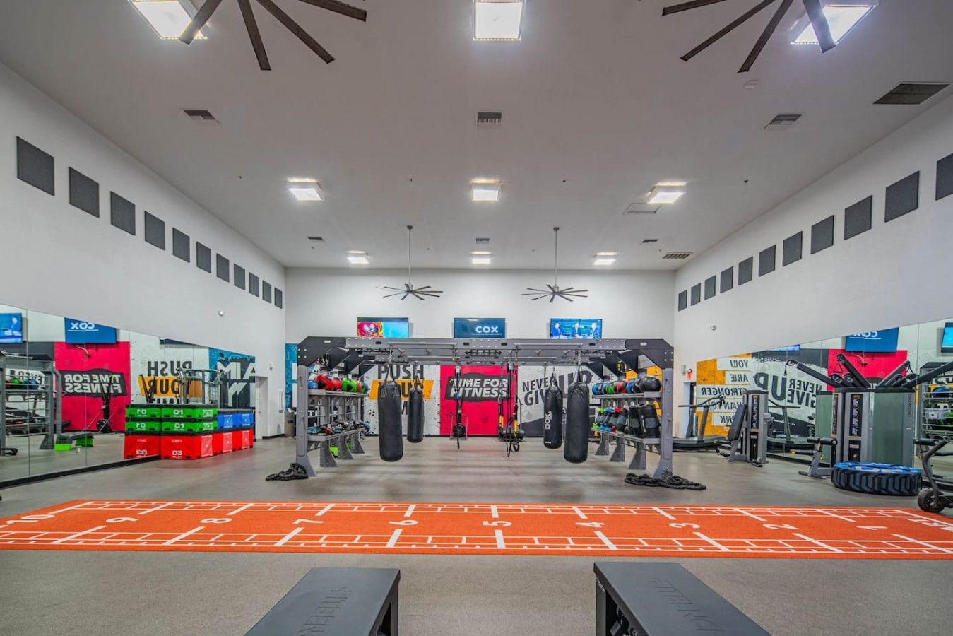 Une salle de sport équipée de divers appareils d’exercice, notamment une barre de traction et des sacs de frappe.