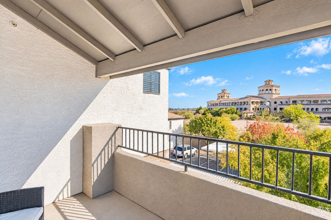 Un balcon donnant sur un immeuble doté d’une tour et d’un parking.