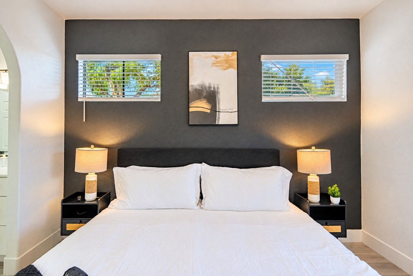 A bedroom with a large bed, two bedside tables with lamps, and three framed pictures on the wall.