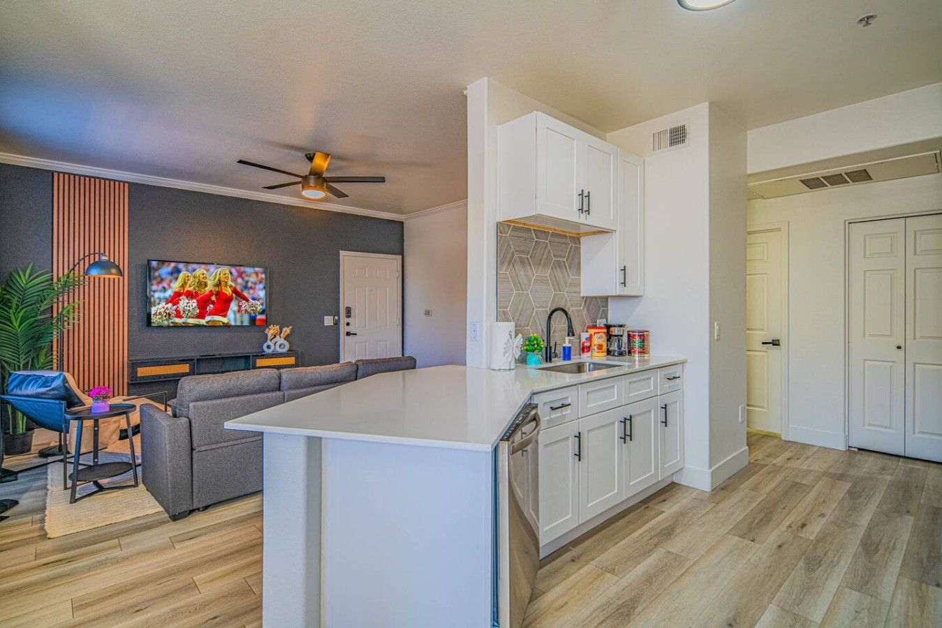 A modern kitchen with white cabinetry, a central island, and a dining area with a sofa and table.