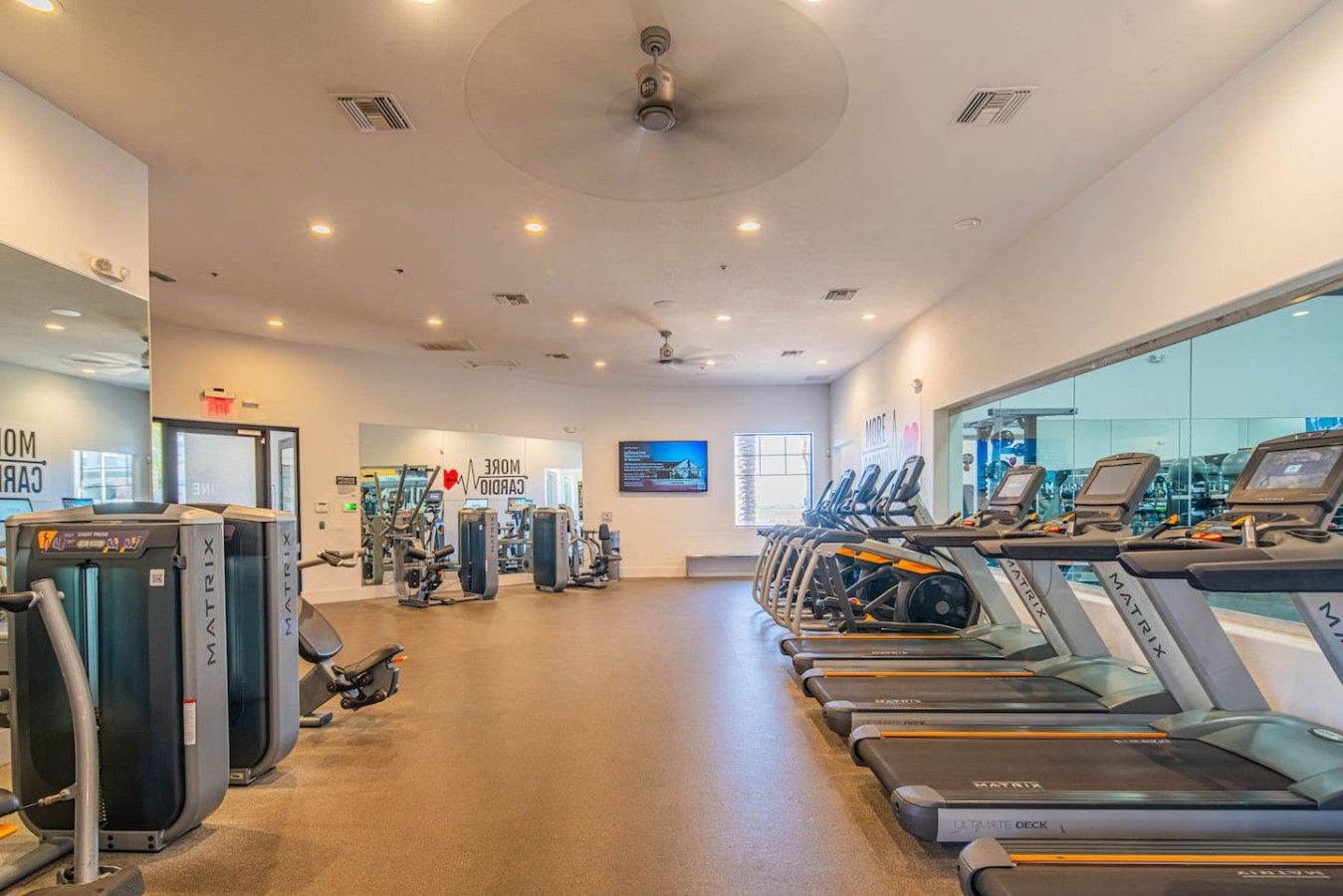 Une salle de sport équipée de tapis de course, d’appareils de musculation et d’un mur recouvert de miroirs.