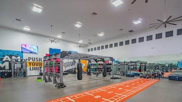 A gym with various exercise equipment, a motivational wall, and a running track.