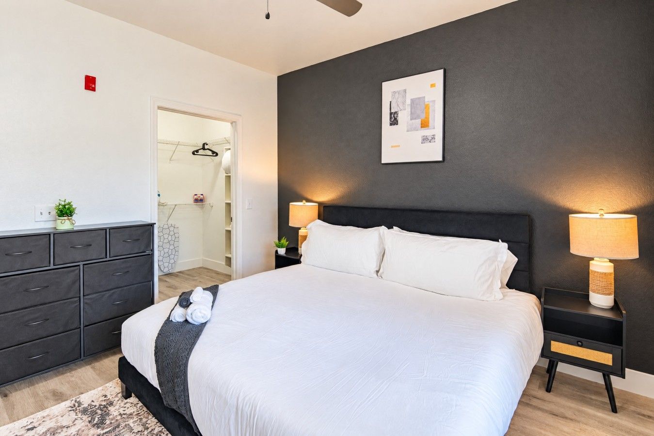 A modern bedroom with a large bed, bedside tables, a wardrobe, and a shower area.