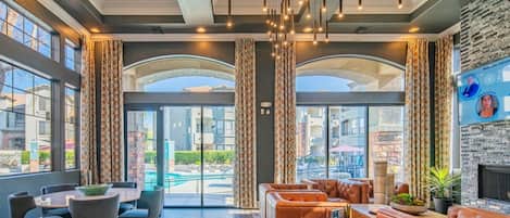 A hotel lobby with a pool view, leather seating, and pendant lighting.