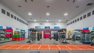 Une salle de sport équipée de divers appareils d’exercice, notamment une barre de traction et des sacs de frappe.