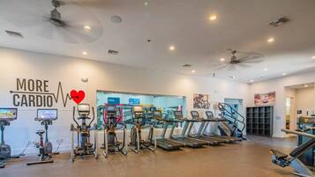 Une salle de sport équipée de machines de cardio, de tapis de course et de vélos d’appartement.