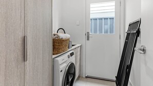 Un cuarto de lavandería con lavadora, tendedero y una cesta con toalla.