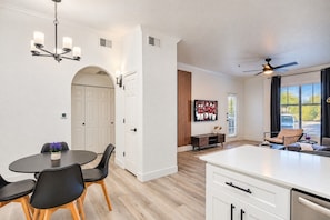 A modern kitchen with a white countertop, black chairs, and a dining table.