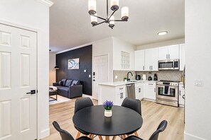 A modern kitchen with white cabinets, a black countertop, and stainless steel appliances.