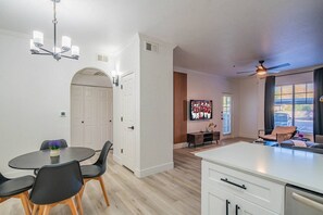 A modern living room with a dining area, a TV, and a ceiling fan.