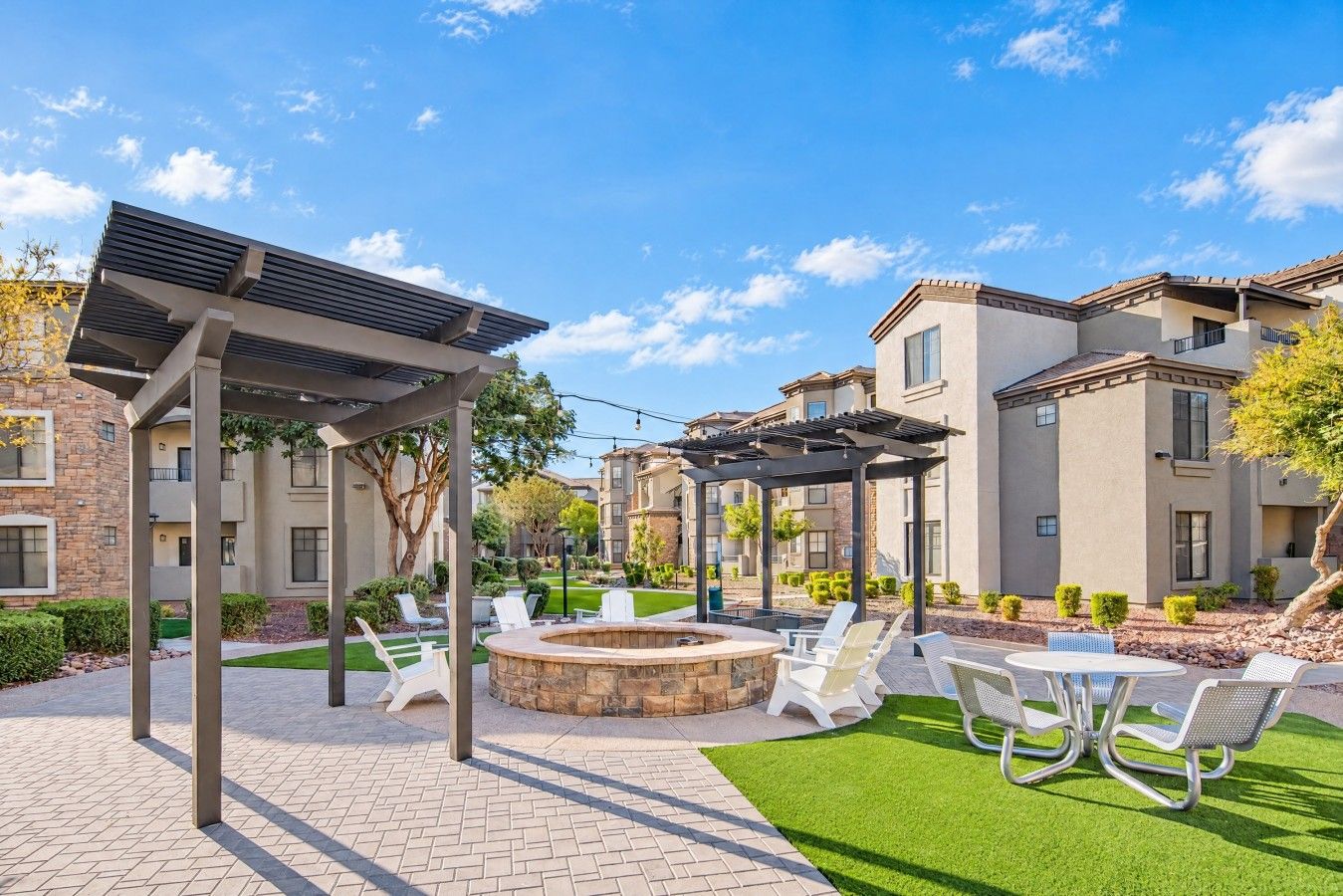 A courtyard with outdoor seating, a fire pit, and a pergola structure.