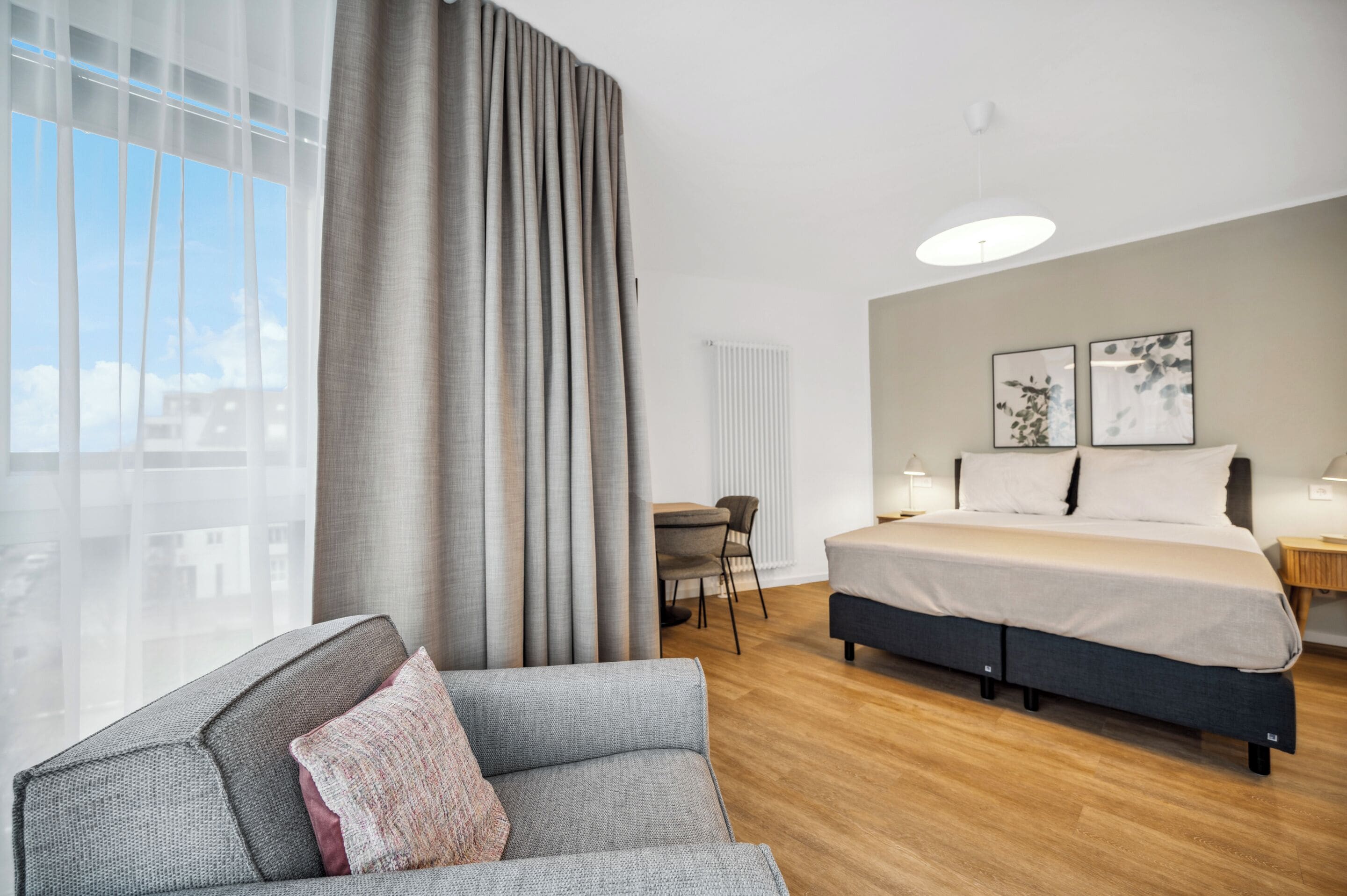Une chambre d’hôtel moderne, dotée d’un grand lit, d’un canapé, d’un bureau et offrant une vue sur la ville.