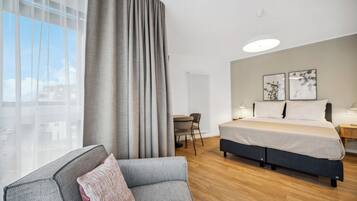 Une chambre d’hôtel moderne, dotée d’un grand lit, d’un canapé, d’un bureau et offrant une vue sur la ville.
