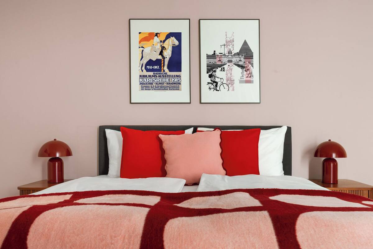 Une chambre d’hôtel avec un lit, deux tables de chevet et deux tableaux encadrés au mur.