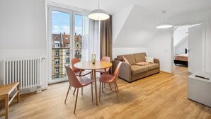 Un appartement moderne comprenant un coin repas, un canapé et une vue sur les immeubles.