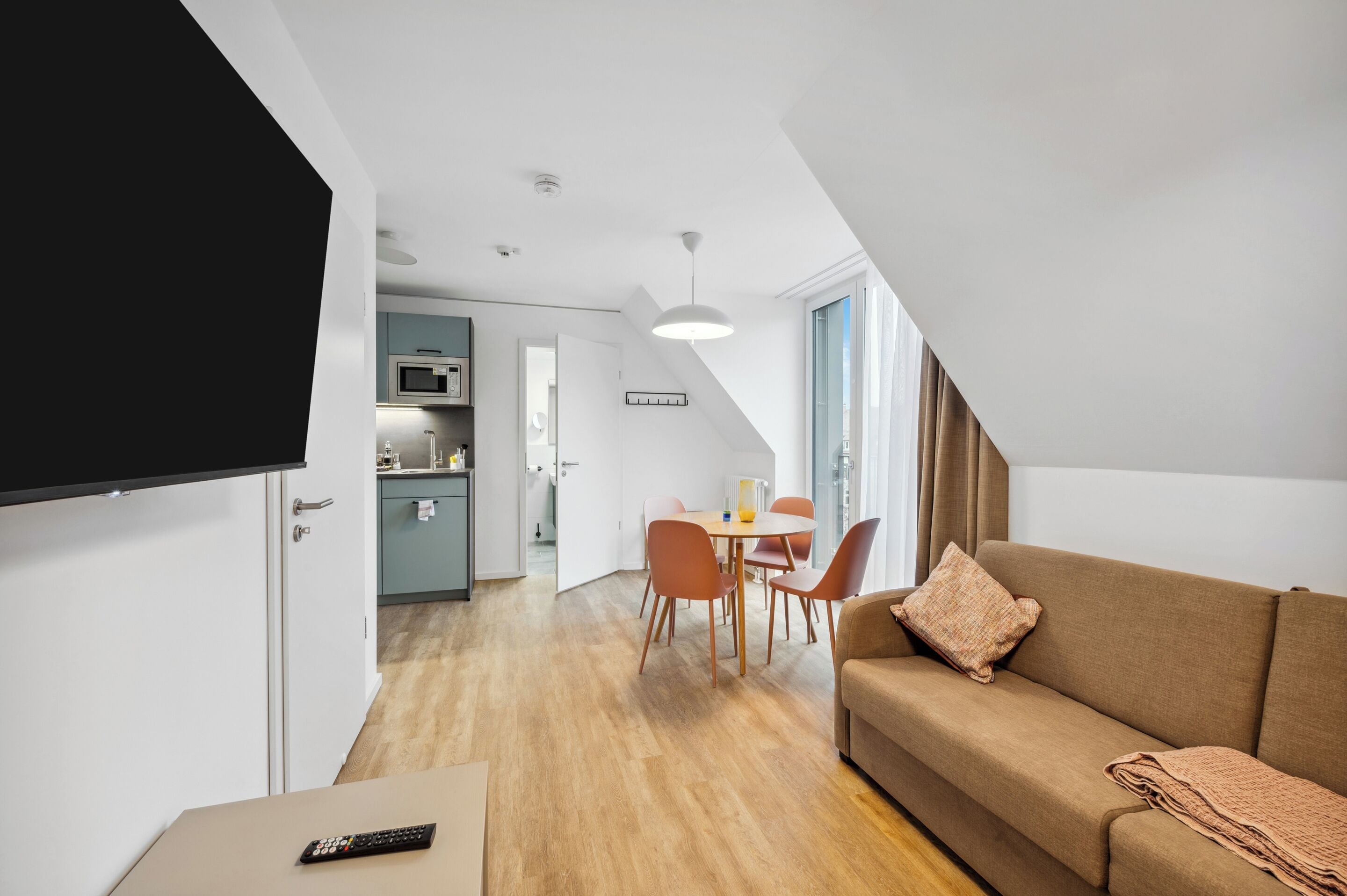 Eine moderne Wohnung mit Essbereich, einer Couch und einer Küche im Hintergrund.