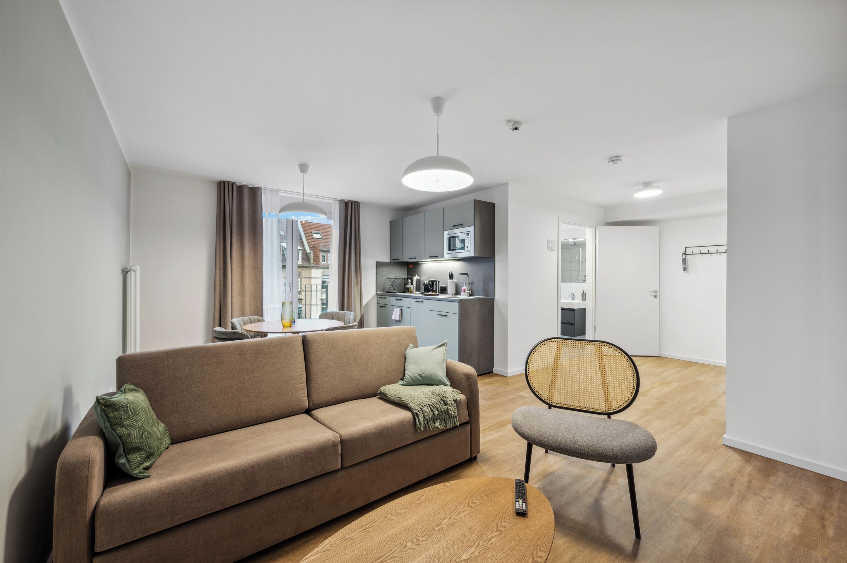 A modern living room with a sofa, a chair, and a dining area.