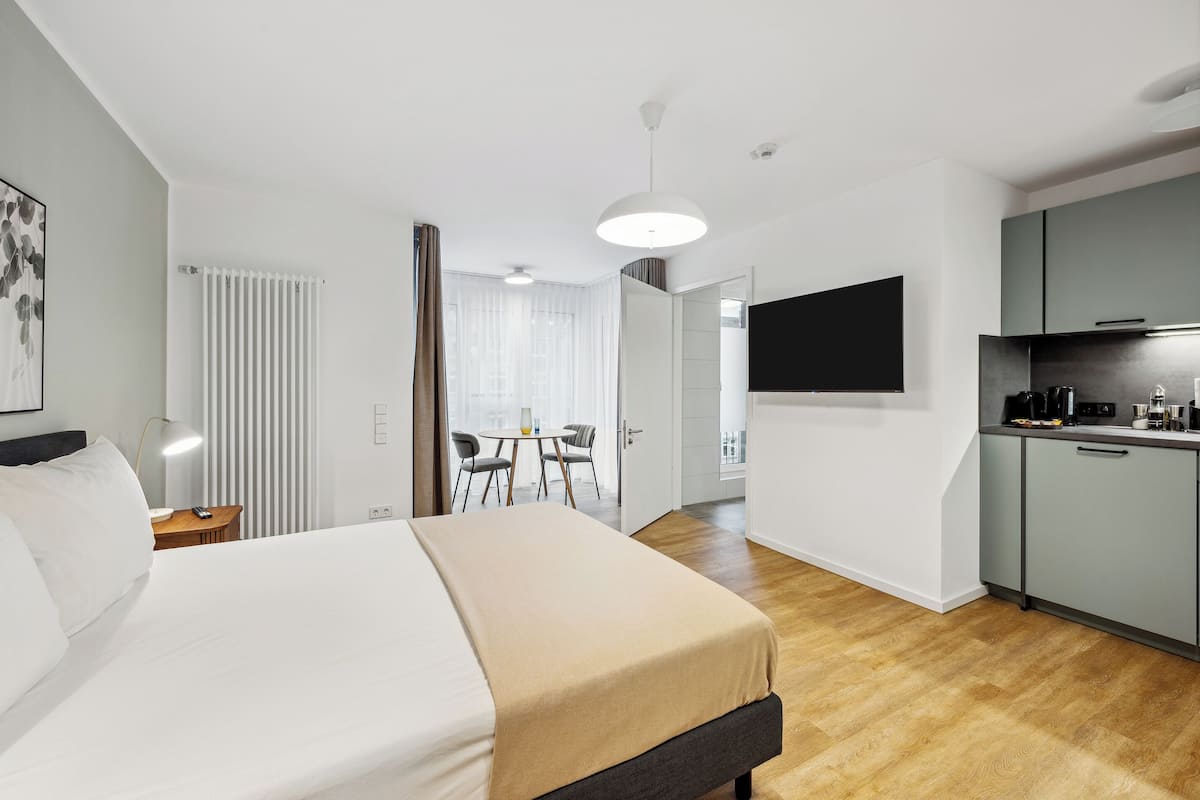 Une chambre d’hôtel moderne dotée d’un grand lit, d’une kitchenette et d’un coin repas avec une table et des chaises.