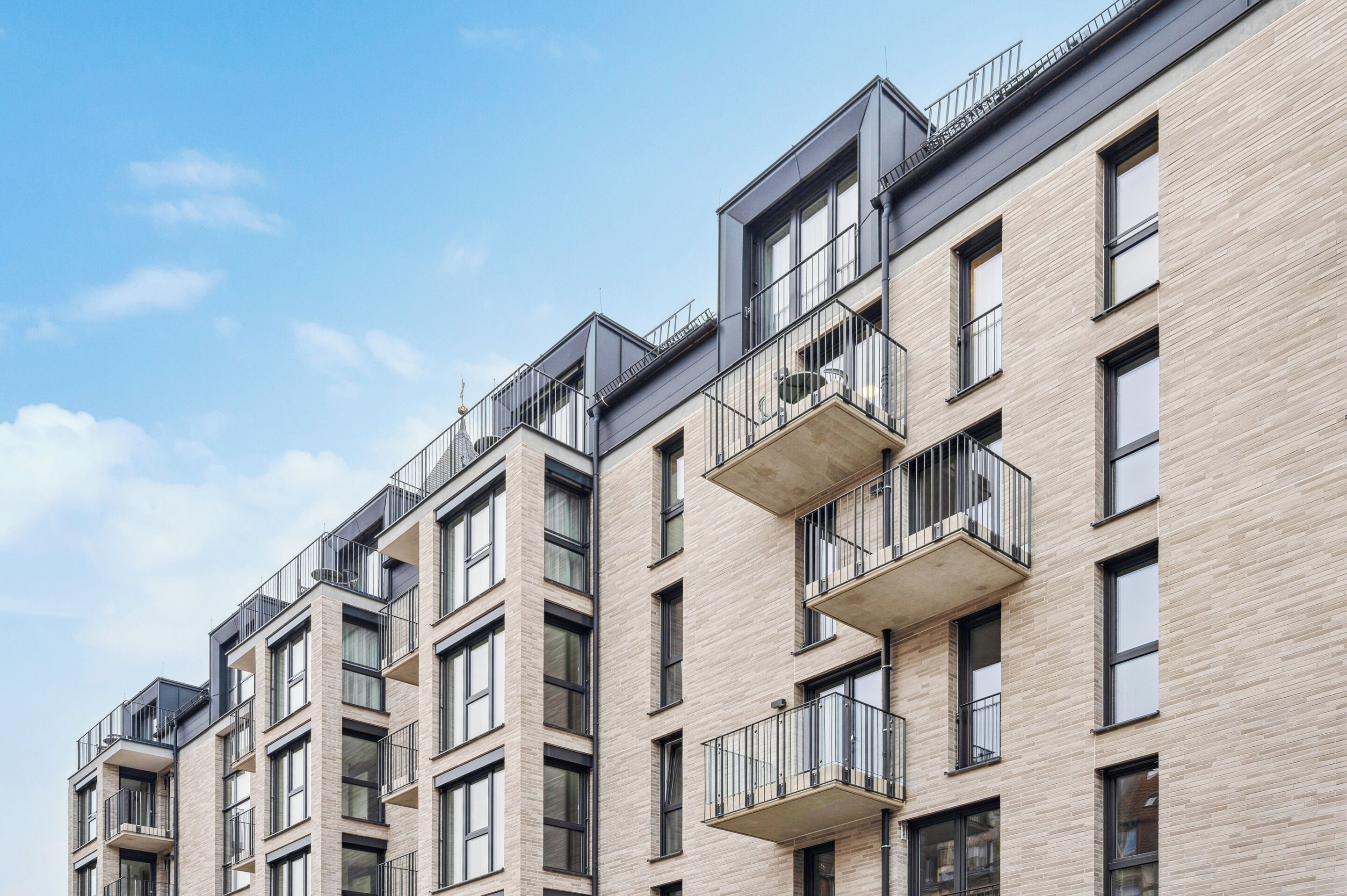A multi-story residential building with balconies, large windows, and a modern architectural design.