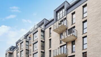 A multi-story residential building with balconies, large windows, and a modern architectural design.