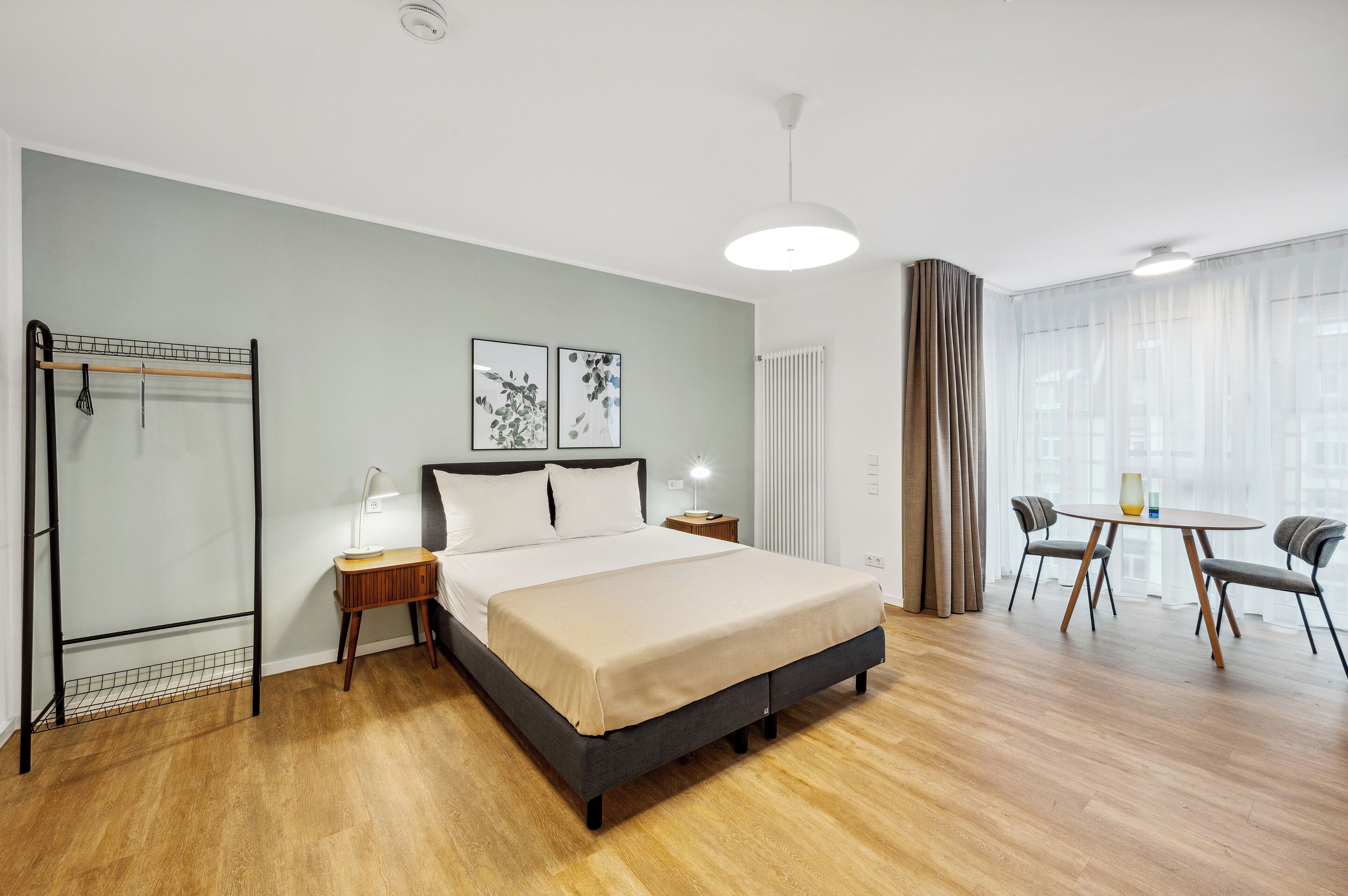 Une chambre d’hôtel moderne équipée d’un lit, d’une table de chevet, d’une lampe et d’un coin repas avec des chaises et une table.