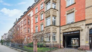 Un bâtiment historique aux détails architecturaux raffinés, une rue pavée et une clôture en métal.