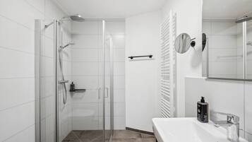 A modern bathroom with a glass-enclosed shower, a white sink, and a mirror.