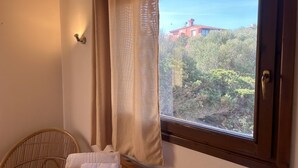 A room with a window, a wooden chair, and a table with towels.