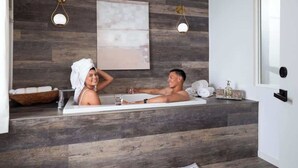 Un baño moderno con pared de madera, un espejo grande y dos luces fijadas a la pared.