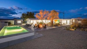 Un hotel moderno con piscina, zona de estar al aire libre y un árbol al fondo.