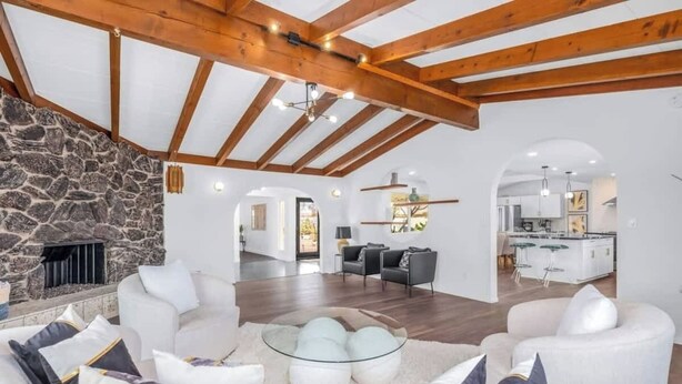 Amplia sala de estar con chimenea de piedra, muebles modernos y una cocina al fondo.