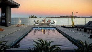 A pool area with two people sitting on chairs, a small pool, and a cactus in the background. - Free Bird • Pool, Spa, Pickleball, Outdoor Lvg Rm! (Joshua Tree)