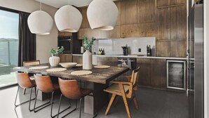 A modern kitchen with a wooden dining table, pendant lights, and a view of the outdoors. - Free Bird • Pool, Spa, Pickleball, Outdoor Lvg Rm! (Joshua Tree)