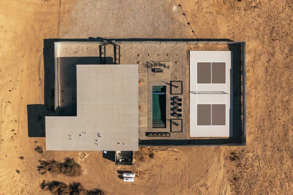 Vue aérienne d’une propriété comprenant un grand bâtiment rectangulaire, une piscine et une construction plus petite attenante.