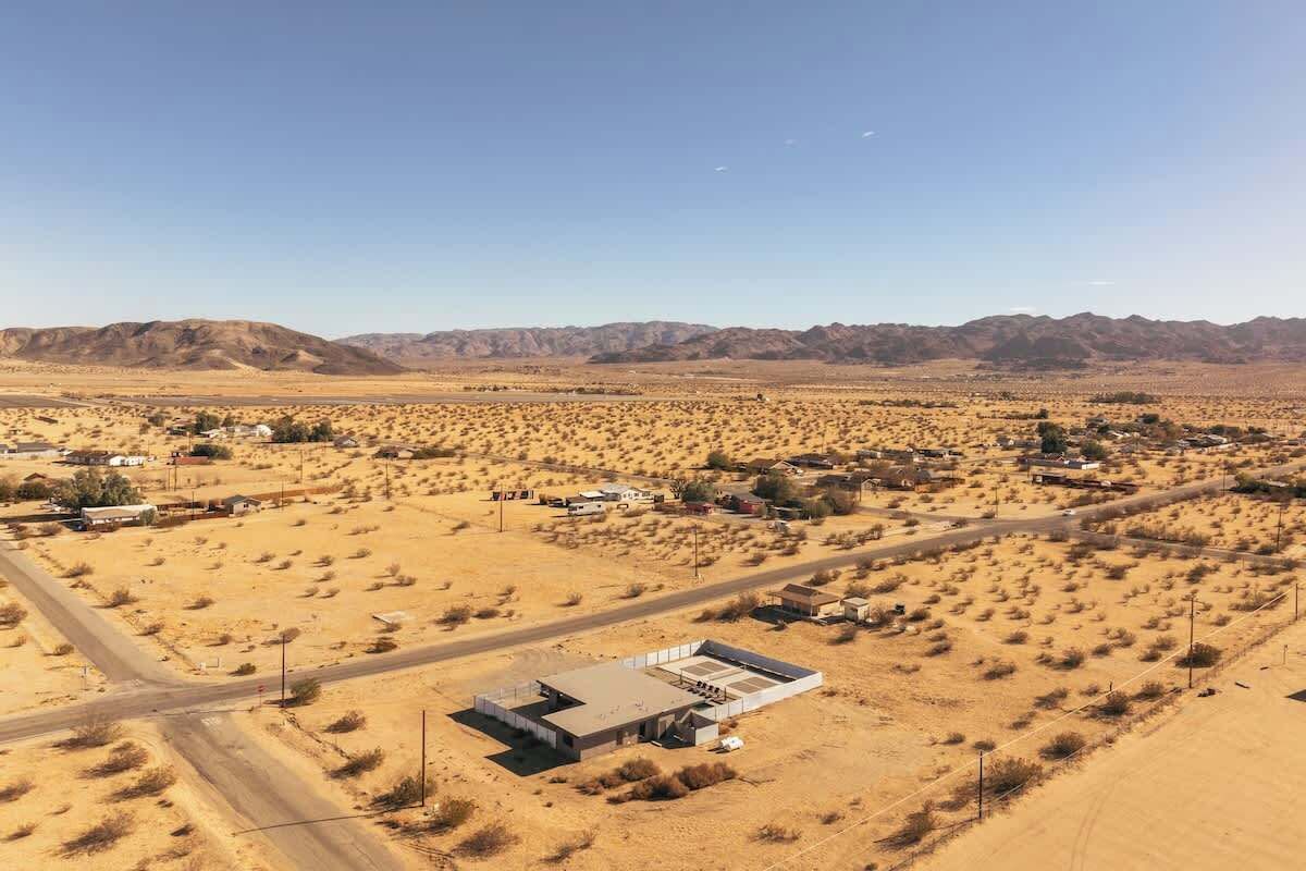 An aerial view of a desert landscape with sparse vegetation and a few buildings.