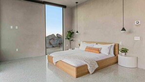 A modern bedroom with a large bed, a sliding glass door, and a view of the outdoors. - Prism • Modern Luxury in Boulders, Pool & Hot Tub (Joshua Tree)