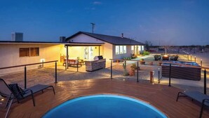 A modern outdoor pool area with lounge chairs, a barbecue, and a patio with a view of the city skyline at dusk. - Winters Haven · 2.5 Acres, Spa, PingPong, SoakPool (Joshua Tree)