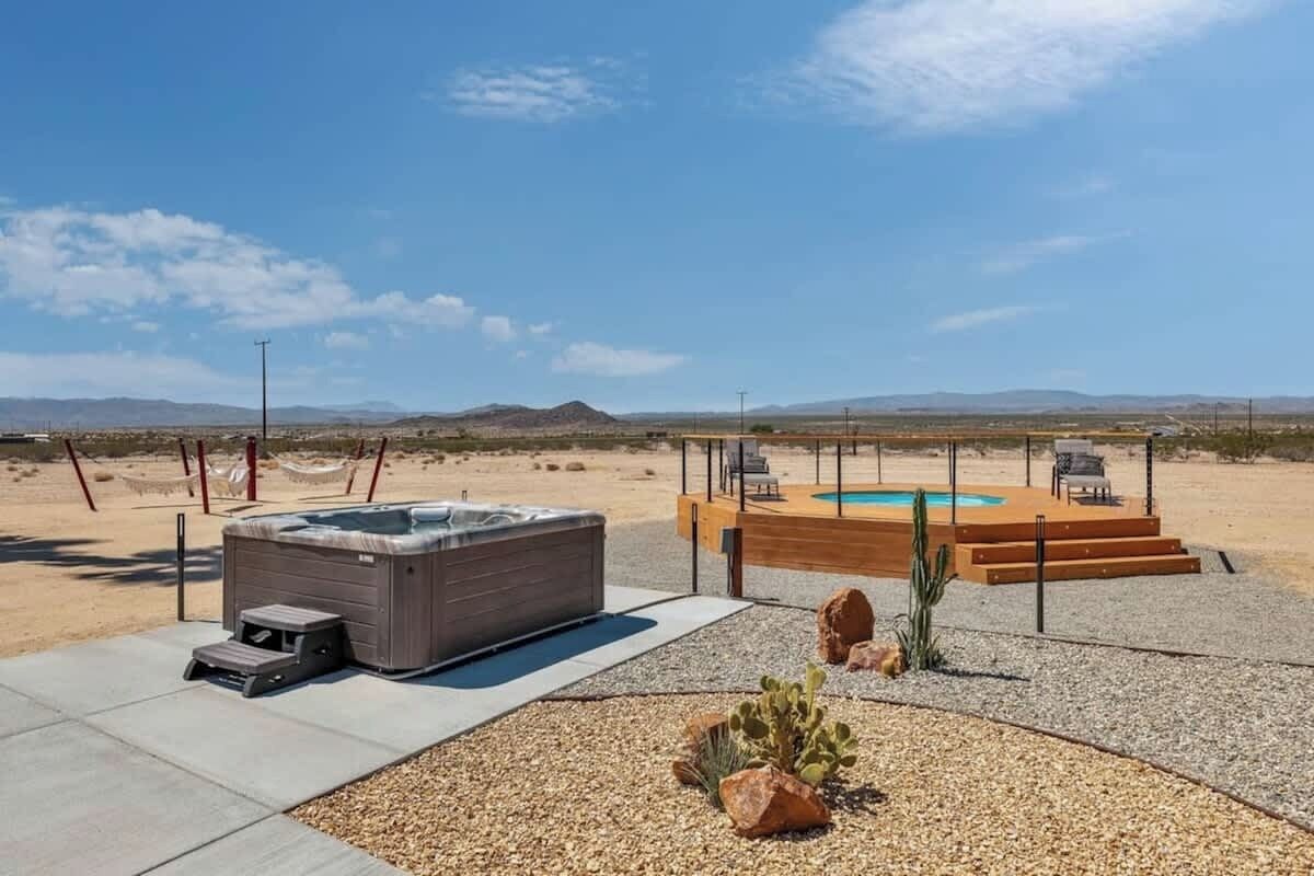 A hot tub and a pool in a desert setting with mountains in the background.