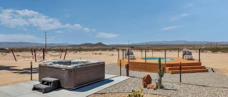 A hot tub and a pool in a desert setting with mountains in the background.