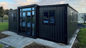 Un bâtiment moderne en métal noir, doté de grandes fenêtres en verre et d’un toit plat.