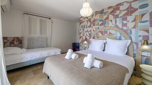 A hotel room with two beds, a patterned wall, a hanging light fixture, and a bedside table with a lamp. - Splendid Flat in Provencal Villa 1br/3p (Grimaud)
