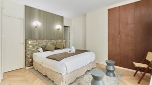 Un dormitorio con cama, un armario de madera, una silla y una mesita.